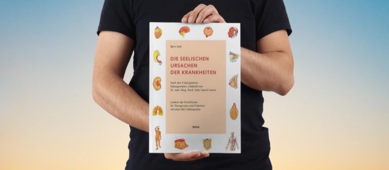 Person hält Buch über die seelischen Ursachen von Krankheiten.