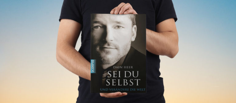 Mann hält Buch "Sie du selbst" von Dain Heer vor seinem Gesicht.