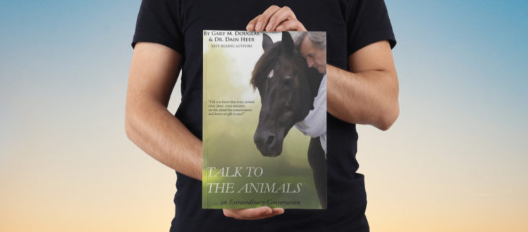 Person hält Hörbuch "Talk to the Animals" mit Pferd im Hintergrund.