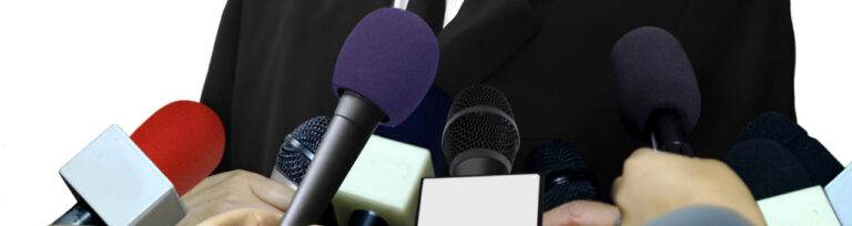 Mikrofone und Reporter bei einer Pressekonferenz.