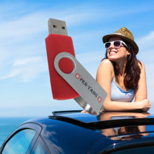 großer roter USB Stick auf den eine glückliche Frau aus einem Auto heraus schaut