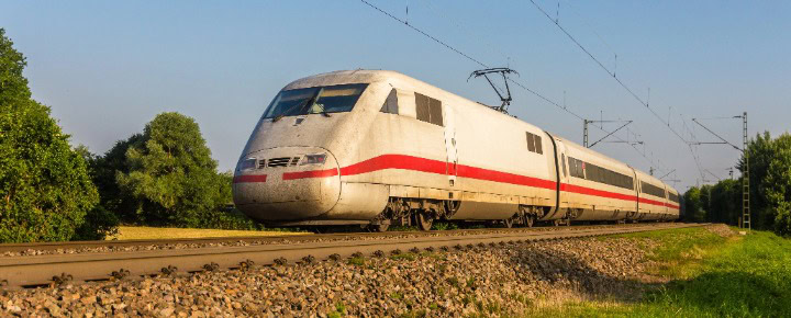 Zug fährt auf Bahnstrecke von rechts nach links.